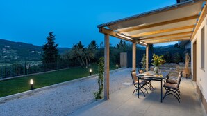 An outdoor patio with a table and chairs, a pergola, and a view of the countryside.
