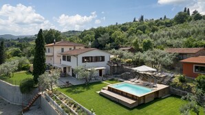 A villa with a swimming pool, a patio with outdoor furniture, and a well-maintained garden.