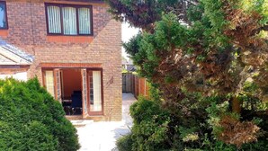 A brick house with a patio, a wooden fence, and a large tree. - Lovely 4-bed , 3 Bath Villa in Bolton, Manchester (Bolton)