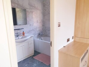 A bathroom with a marble wall, a sink, a bathtub, and a wooden cabinet. - Lovely 4-bed , 3 Bath Villa in Bolton, Manchester (Bolton)