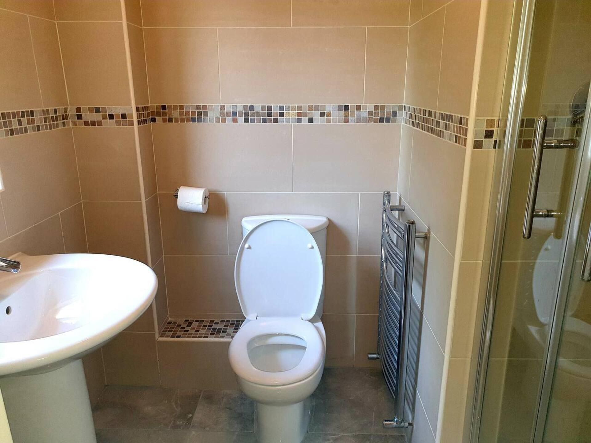 Ein Badezimmer mit Toilette, Waschbecken und Duschbereich.