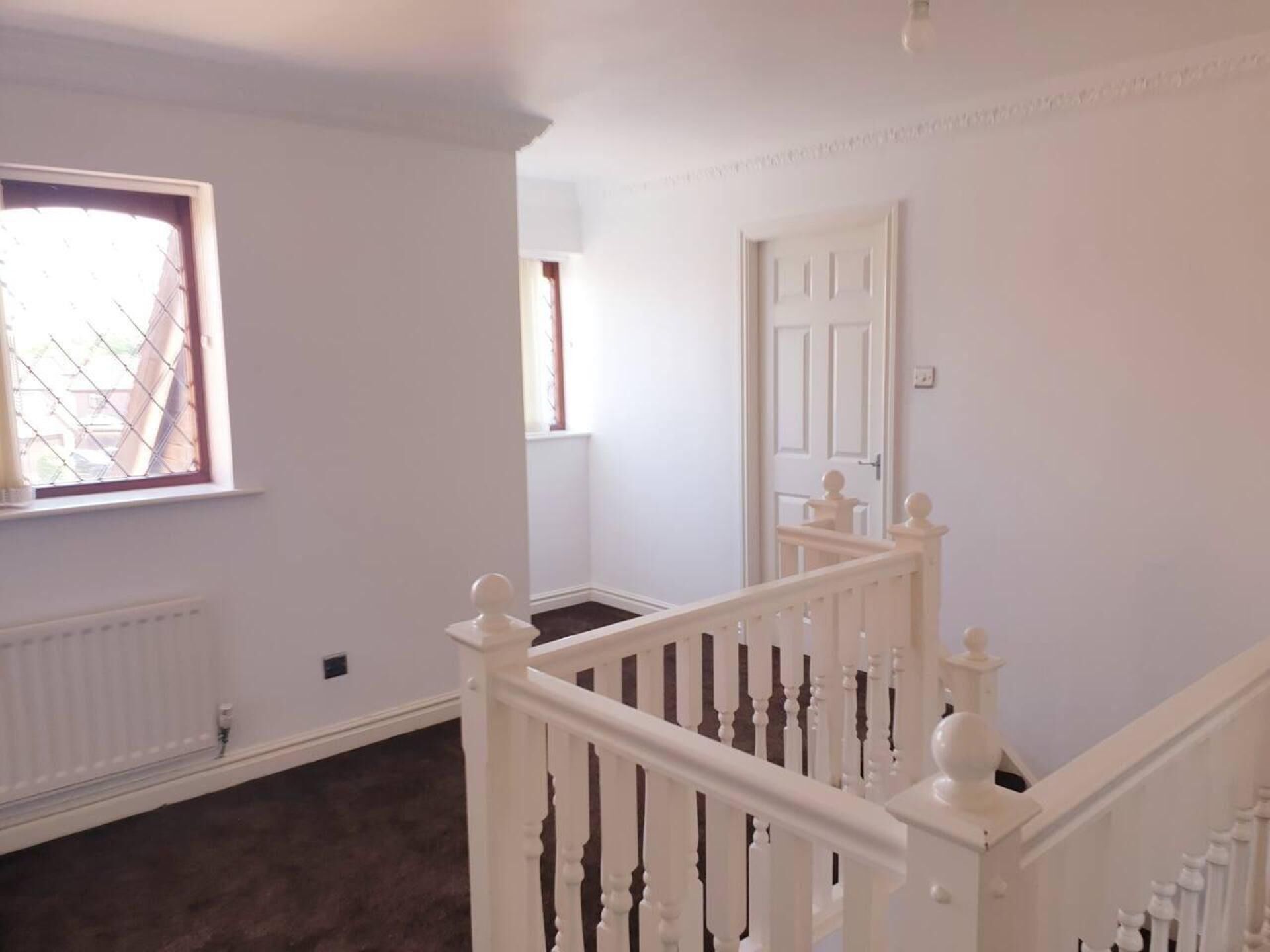 A staircase with white balusters and a handrail, leading to a landing with a door.