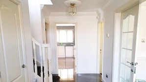 A hallway with a staircase, a door with a frosted glass panel, and a light fixture on the ceiling. - Lovely 4-bed , 3 Bath Villa in Bolton, Manchester (Bolton)