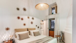 A bedroom with a bed, a nightstand, a chair, a hanging light fixture, and a door leading to another room. - U Quardianu - Le Case di Valentina (Gallipoli)
