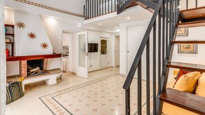 A spacious living area with a fireplace, a staircase, and a view into another room. - U Quardianu - Le Case di Valentina (Gallipoli)