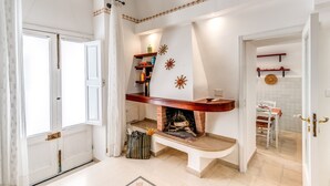 A living room with a fireplace, a dining area, and a kitchen visible through an open door. - U Quardianu - Le Case di Valentina (Gallipoli)