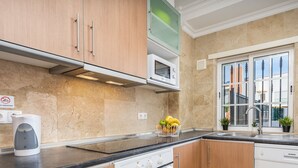 Una cocina moderna con armarios de madera, un microondas integrado y un ventanal con vistas al exterior.