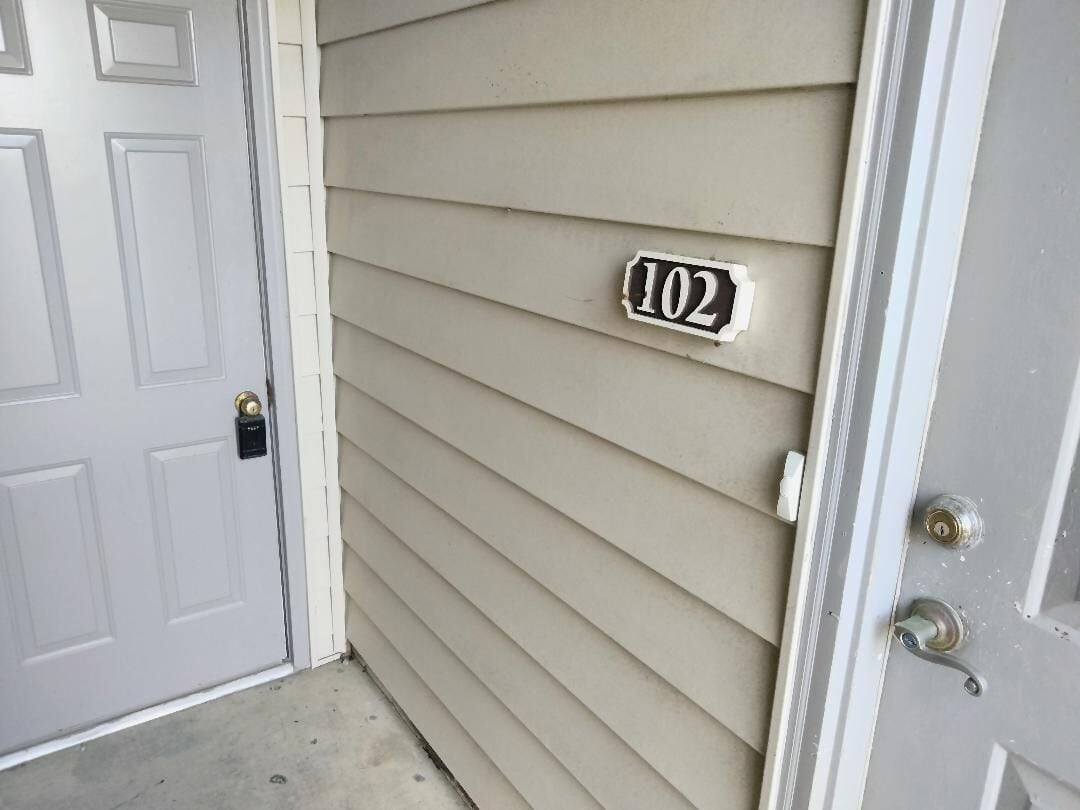 A house number '102' on a beige siding wall.