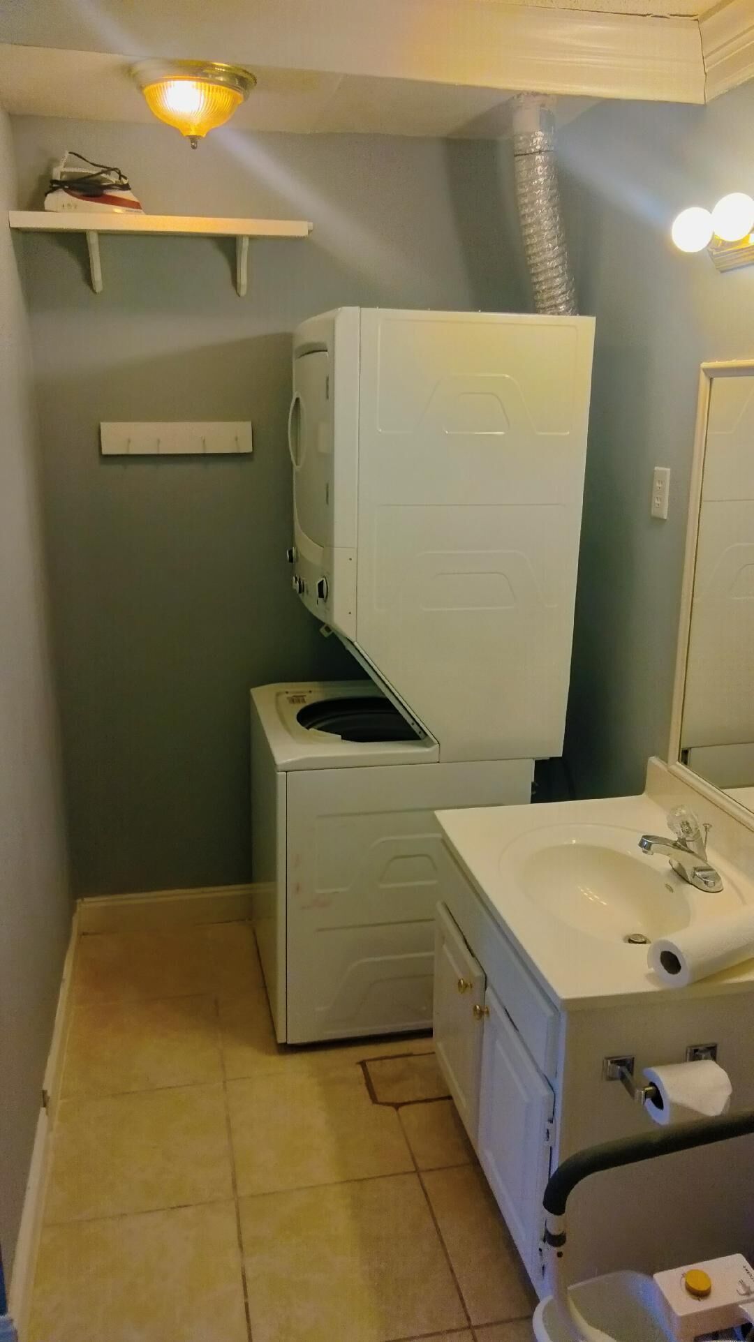 Une petite salle de bain équipée d’un lave-linge, d’un petit lavabo et d’un miroir.