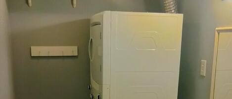 Une petite salle de bain équipée d’un lave-linge, d’un petit lavabo et d’un miroir.