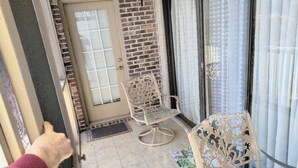 A balcony with two chairs, a door, and a window with curtains. - Unique 2 BR, 2 Bath Condo in Surfside Beach, SC;  Central Grand Strand (Surfside Beach)