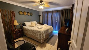 A hotel room with a bed, a desk, a chair, a ceiling fan, and a TV. - Unique 2 BR, 2 Bath Condo in Surfside Beach, SC;  Central Grand Strand (Surfside Beach)