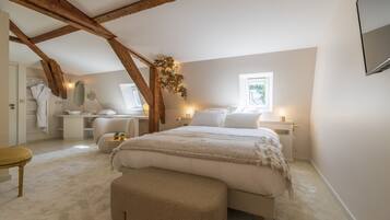 A bedroom with a large bed, a desk, a chair, and a window.