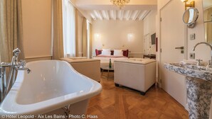 A luxurious bathroom with a freestanding bathtub, a sofa bed, and a marble sink.