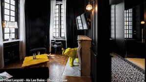 A dark-themed hotel room with a large window, a yellow table with glasses, and a yellow elephant sculpture.