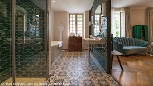 A hotel bathroom with a glass shower enclosure, a bathtub, and a vanity with a sink.