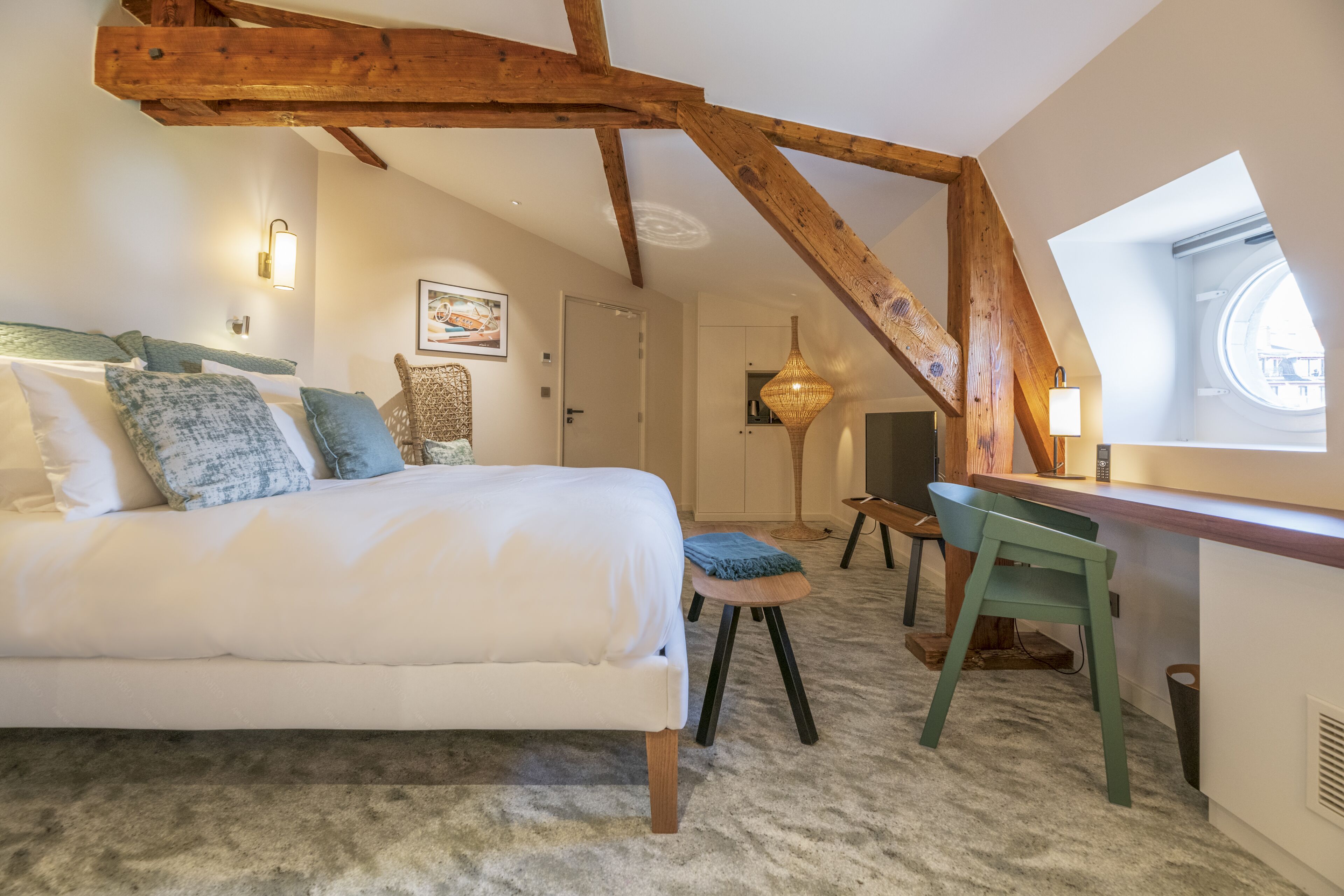 A bedroom with a large bed, a desk, and a window.