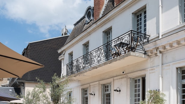 A courtyard with outdoor seating, potted plants, and a building with a balcony.