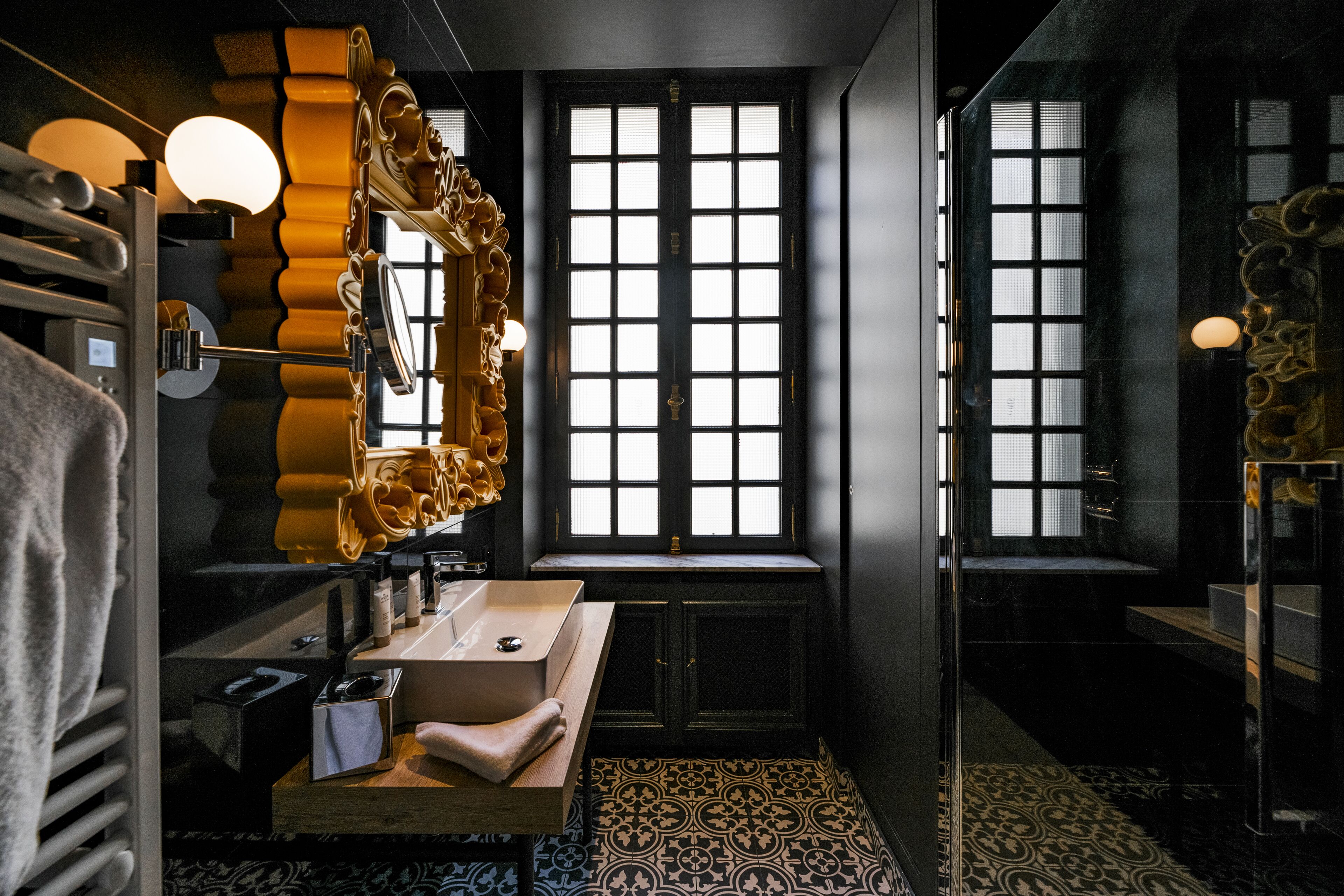 A bathroom with a large mirror, a sink, and a window.