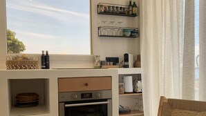 A modern kitchen with a built-in oven, a window with a view, and a cozy seating area with a woven chair.