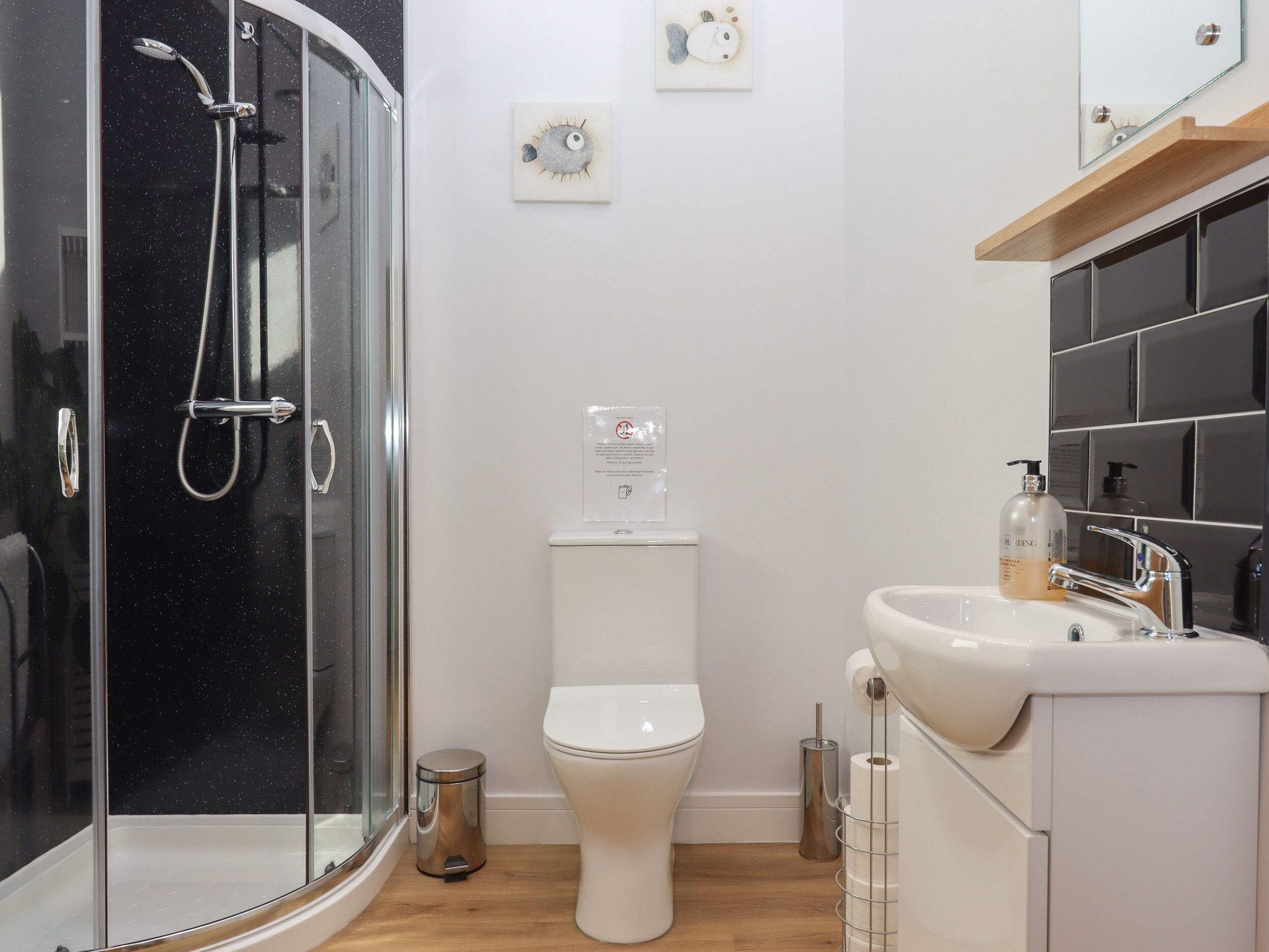 A modern bathroom with a glass-enclosed shower, a white toilet, and a sink with a mirror above it.