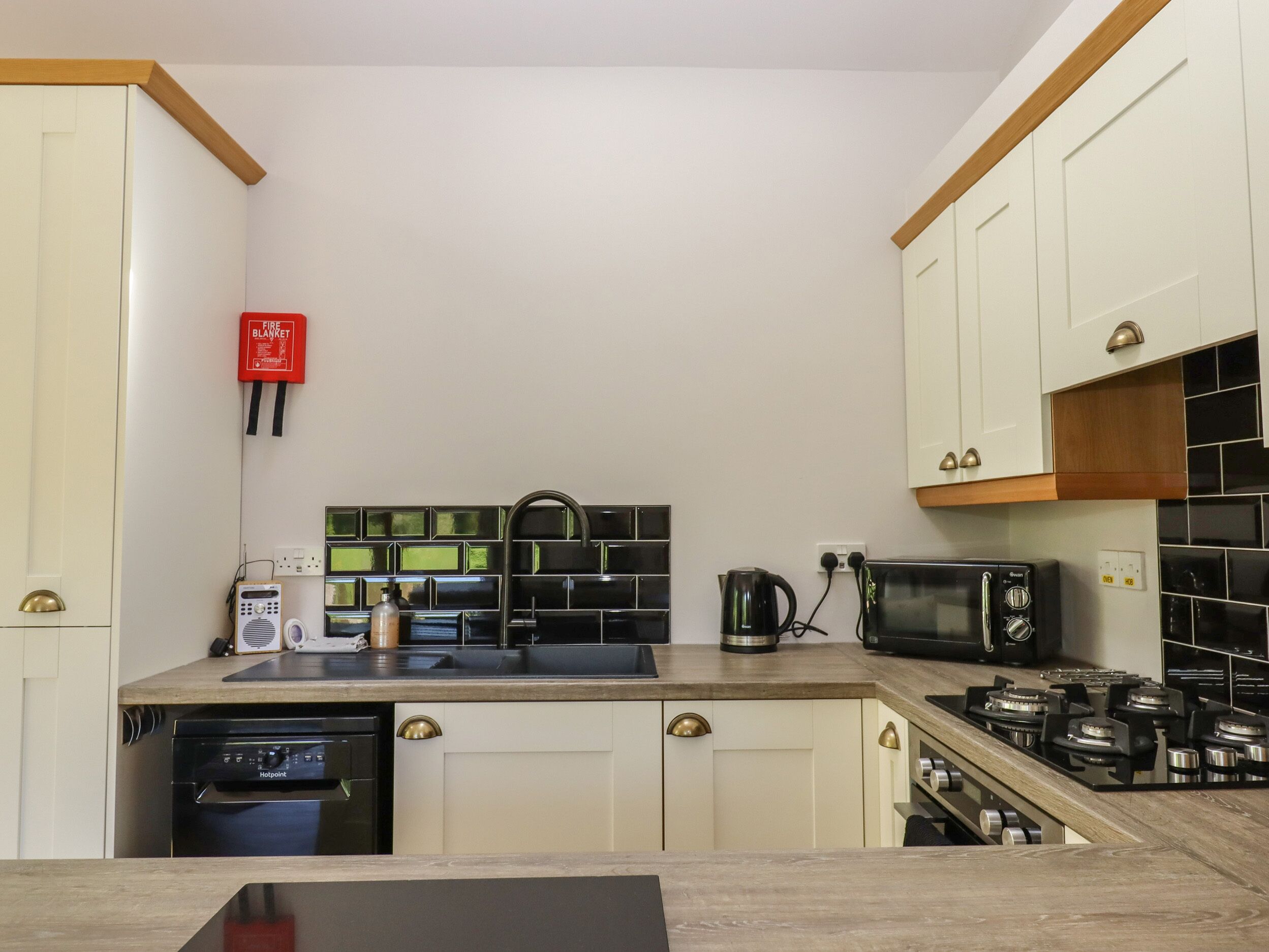 A compact kitchen with white cabinets, a black microwave, a gas stove, and a coffee maker.