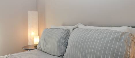 A neatly made bed with striped bedding and a bedside lamp.