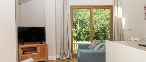 A modern living room with a television, sofa, and a dining area.