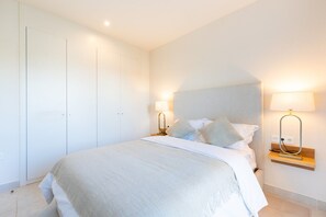 A bedroom with a bed, bedside tables, and a wardrobe.