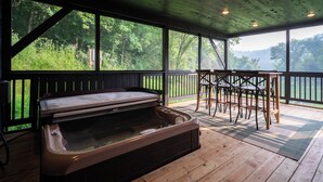 A hot tub in a wooden deck area with a view of a forest. - Private Driftless Cabin w/ Hot Tub, Fireplace & Creekside Views (Ferryville)