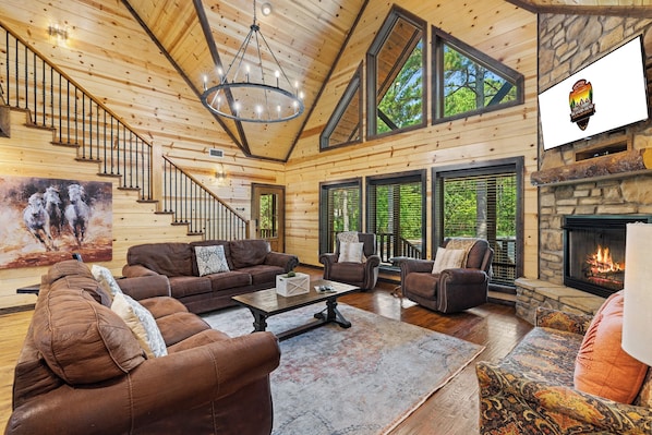 Cozy cabin interior with a high ceiling, fireplace, and leather sofas.