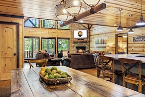Cozy cabin interior with a dining table, comfortable seating area, and a fireplace.