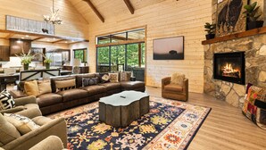 A spacious living room with a stone fireplace, a large sofa, and a coffee table. - Bison's Bend in Hochatown/Broken Bow, OK (Broken Bow)