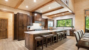 A spacious kitchen with a large island, wooden cabinets, and a view of the outdoors. - Bison's Bend in Hochatown/Broken Bow, OK (Broken Bow)