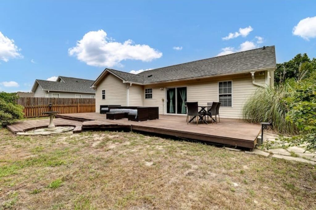 A house with a deck, outdoor seating, and a small garden area.