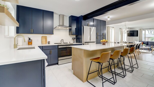 A modern kitchen with dark blue cabinets, a central island with bar stools, and a large island sink. - Hot Tub, Fire Pit, Ping-Pong, 3 min walk to Olde Town Arvada! (Arvada)