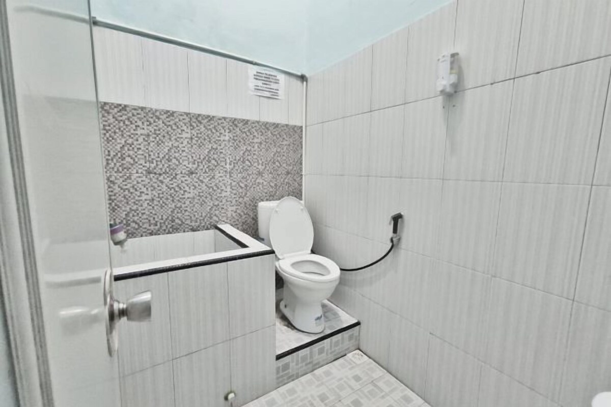 A small, compact bathroom with a toilet, a shower area, and a tiled floor.