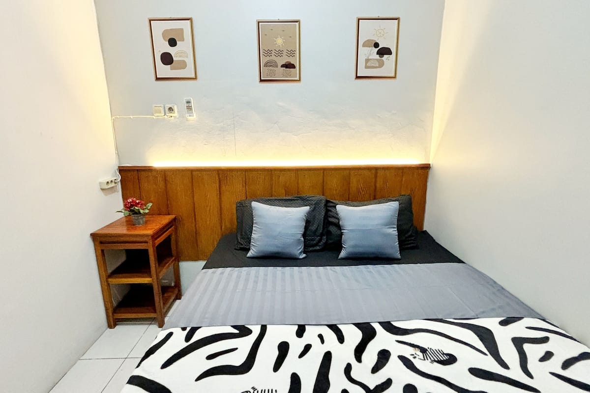 A bedroom with a wooden headboard, a zebra-patterned bedspread, and three framed pictures on the wall.