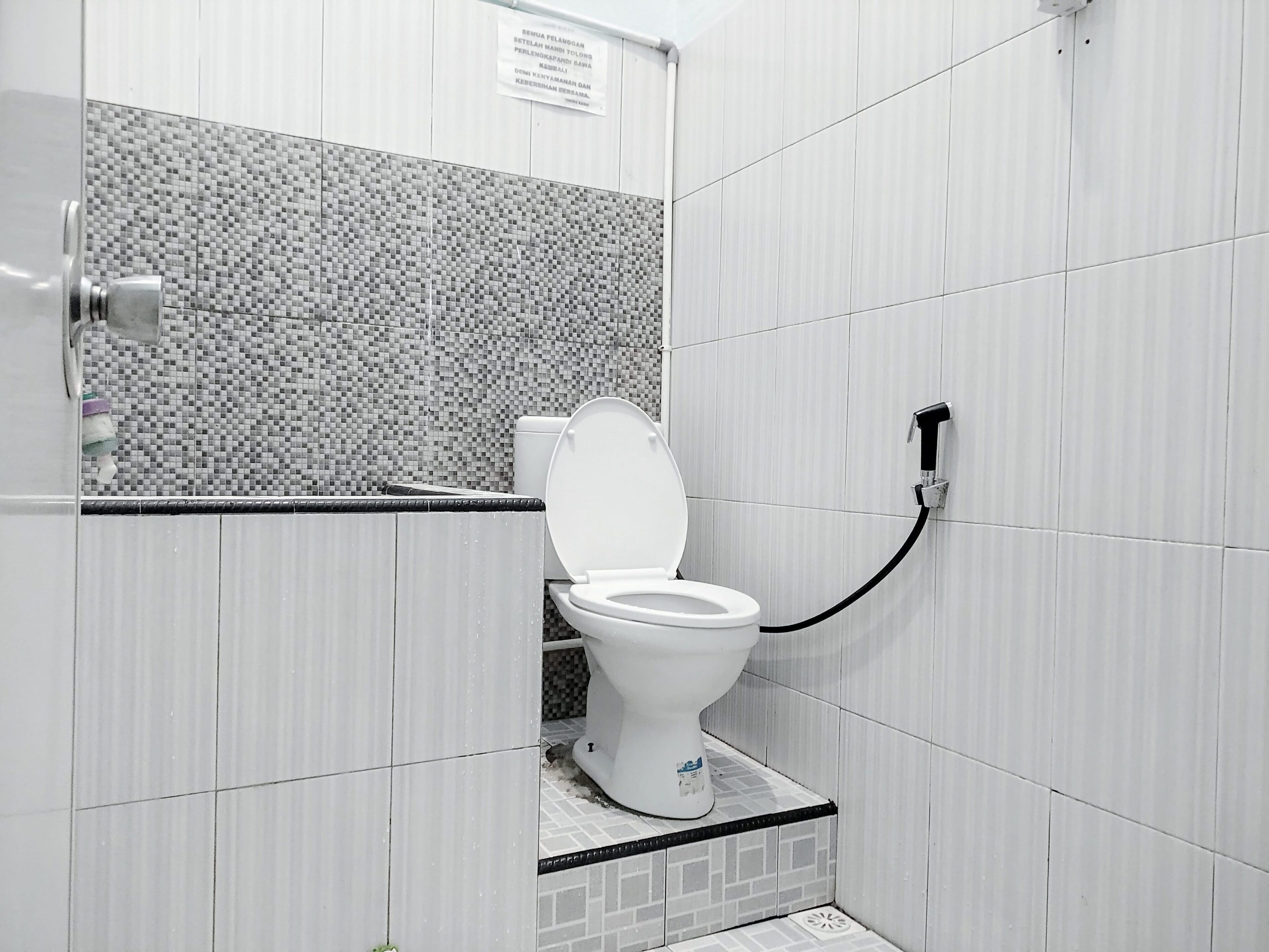 A small, modern bathroom with a toilet, a shower, and a tiled wall.