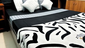 A bed with a zebra print blanket, white and gray striped pillows, and a black headboard. - NgeKost harian (Semarang)