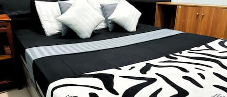 A bed with a zebra print blanket, white and gray striped pillows, and a black headboard.