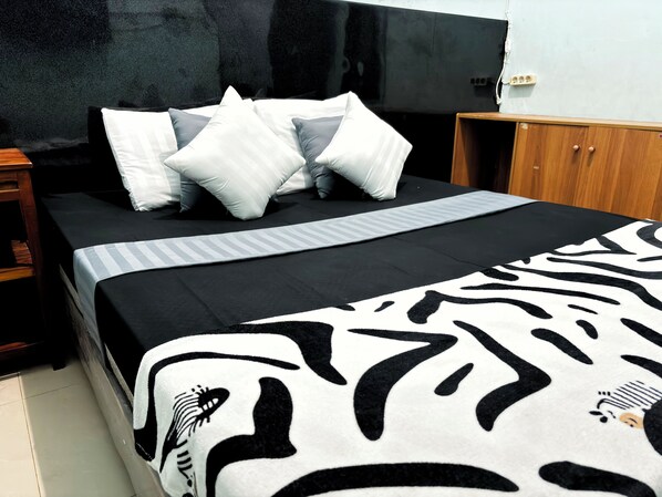 A bed with a zebra print blanket, white and gray striped pillows, and a black headboard.