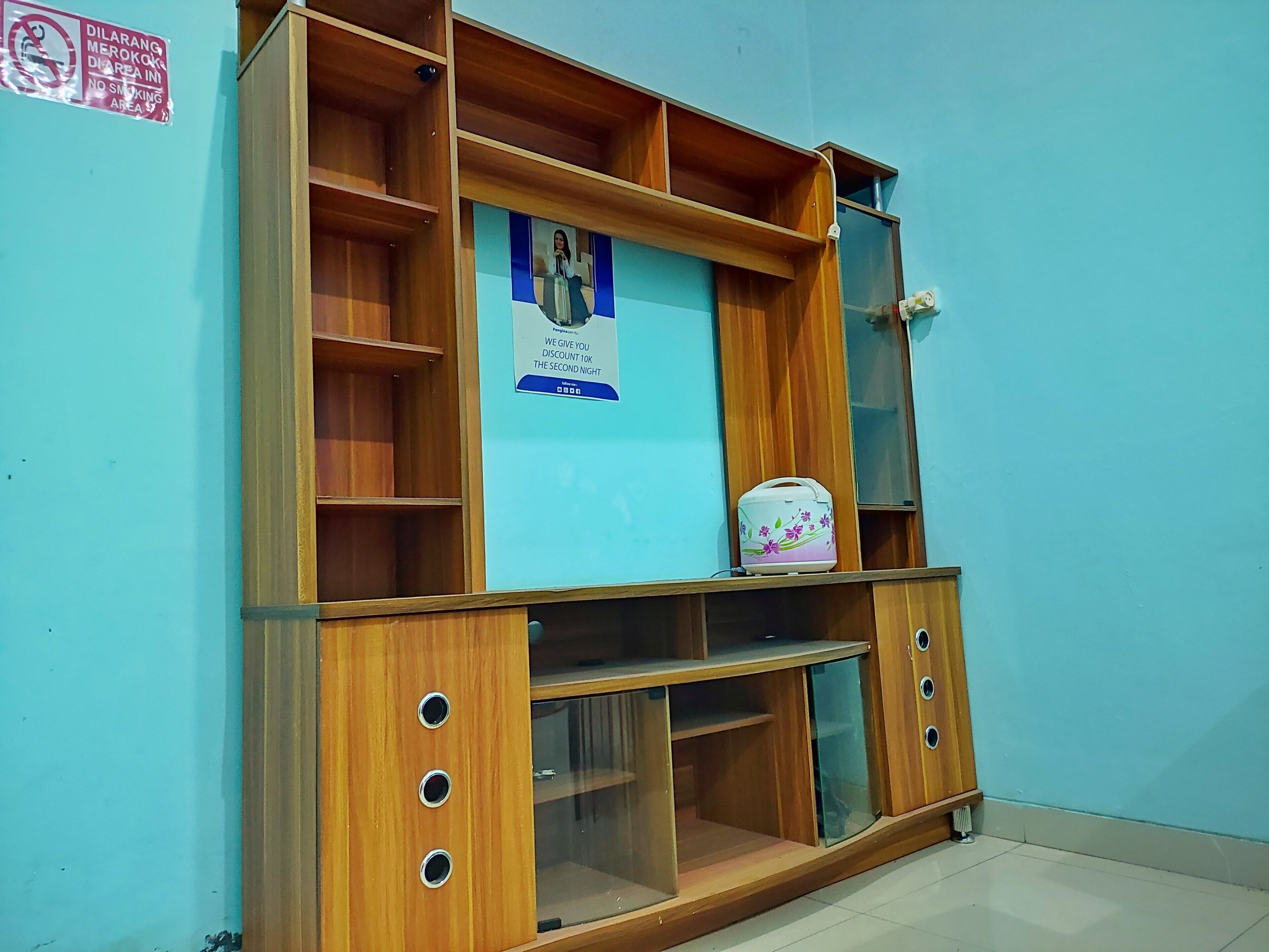 Un mobile in legno con diversi ripiani e una vetrina, un poster sul retro e una piccola borsa sullo scaffale superiore.
