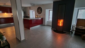 A modern kitchen with red cabinets, a central island, and a built-in fireplace. - Gîte le Fortunio-Gîte-Family-Ensuite with Bath (RIEUTORT DE RANDON)