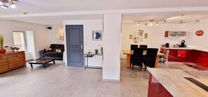 A modern living room with a sofa, coffee table, and a dining area with chairs and a table. - Gîte le Fortunio-Gîte-Family-Ensuite with Bath (RIEUTORT DE RANDON)