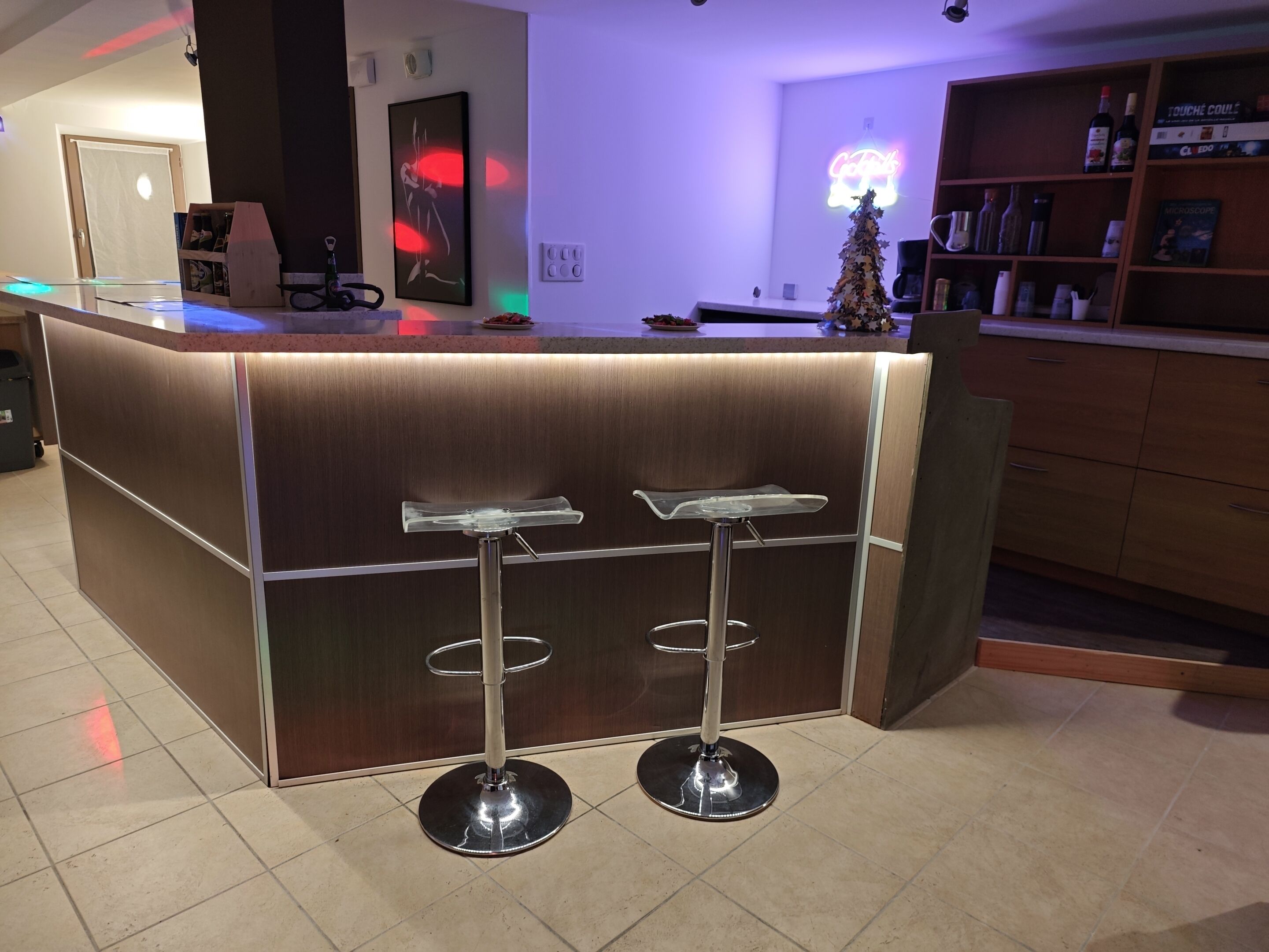 Un espace bar moderne avec un comptoir en bois, deux tabourets de bar et un petit sapin de Noël.