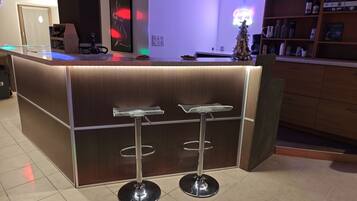 Un espace bar moderne avec un comptoir en bois, deux tabourets de bar et un petit sapin de Noël.