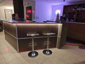 A modern bar area with a wooden counter, two bar stools, and a small Christmas tree. - Gîte le Fortunio-Gîte-Family-Ensuite with Bath (RIEUTORT DE RANDON)