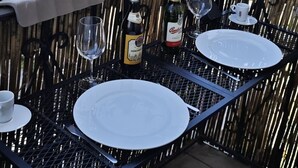 Un balcon avec une table dressée pour deux personnes, une bouteille de vin et un verre.