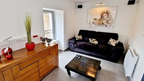 A modern living room with a wooden cabinet, a black coffee table, a dark sofa, and a painting on the wall. - Gîte le Fortunio-Gîte-Family-Ensuite with Bath (RIEUTORT DE RANDON)